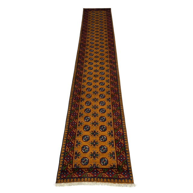 This extra-long Turkmen-style wool runner has a warm terracotta brown field with two rows of repeating octagonal motifs....