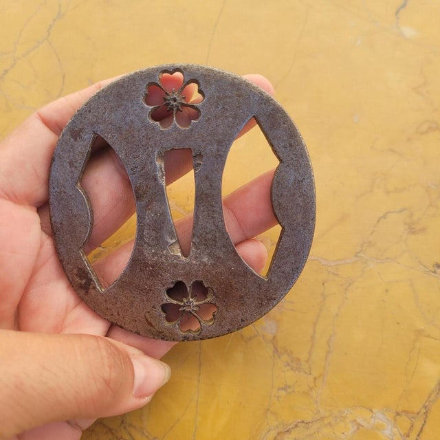 A very refined, round iron tsuba, known as Maru-Gata, with openwork (sukashi) featuring five-petaled Sakura cherry blossom...