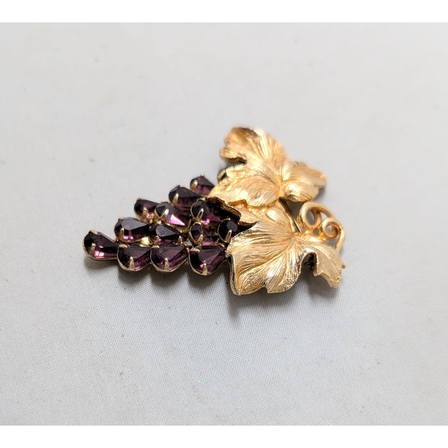 1960s goldtone leaves at the top with tear drop shaped faux-amethyst grape cluster brooch with security clasp. Marked...