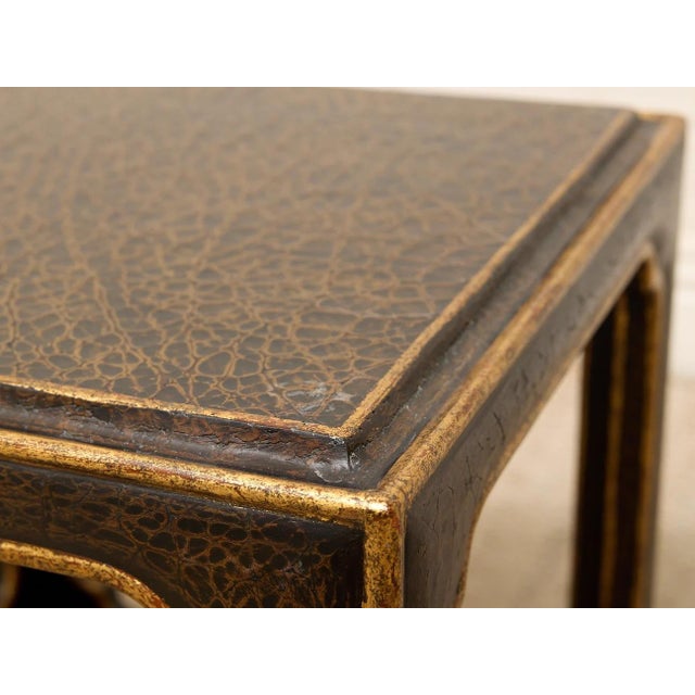 A handsome vintage side table with a richly textured black surface and warm antiqued gold detailing. The tabletop has a...