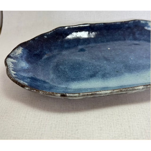 A pair of oval serving plates by Japanese potter Seigan Yamane (山根清玩), each glazed in deep cobalt that pools from a pale...