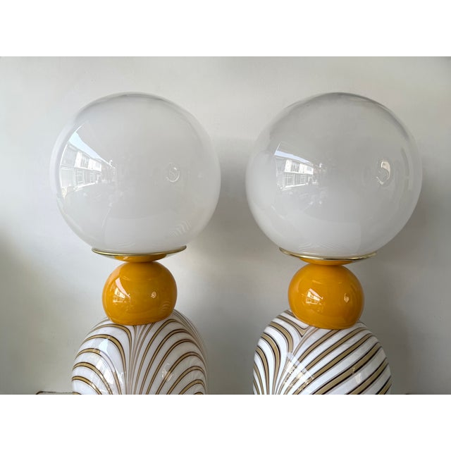 Pair of table or bedside lamps in brass, and orange and white Berlingo stripe Murano glass white smoke globe shades....