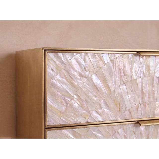 A sculptural statement in natural mother-of-pearl and brushed brass, the Arcana Dresser combines luminous surface artistry...