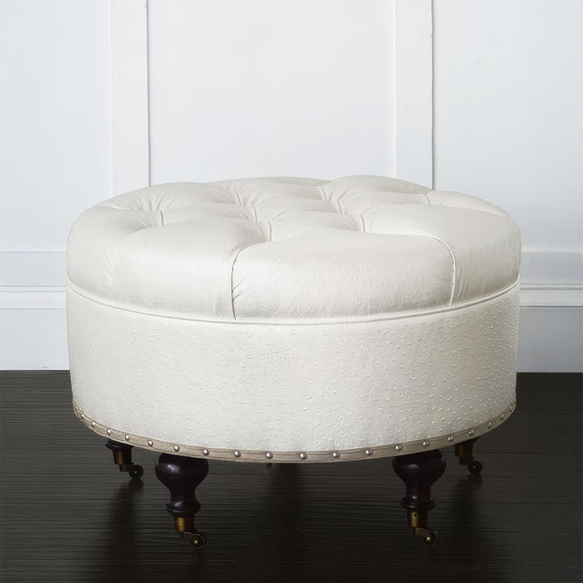Bench-made in the USA, this ottoman features deep button tufting and a plush, dotted faux ostrich leather upholstery in...