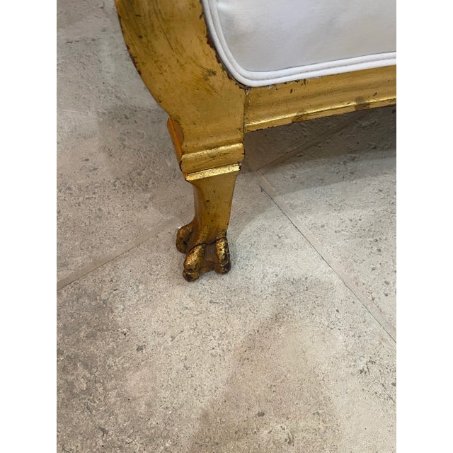 An antique French set featuring two arm chairs and a sofa, each piece is composed of a gilded wood frame decorated by hand...