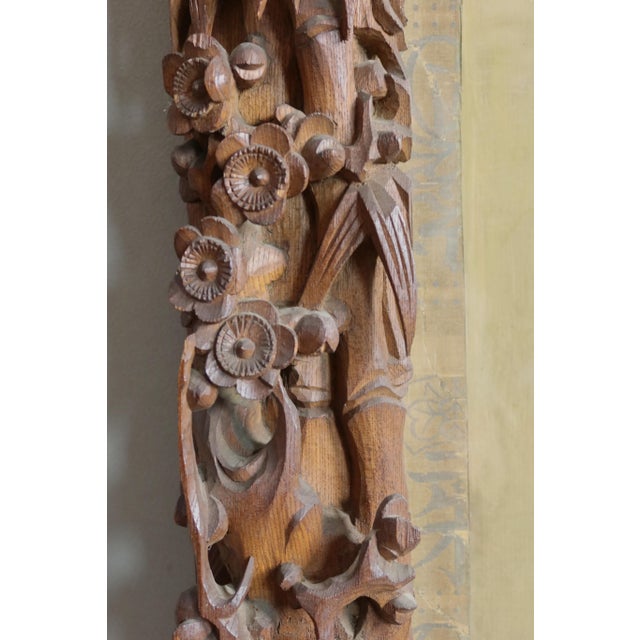 Large carved wooden frame decorated with birds, flowers, and bamboo leaves. A painting or watercolor decorates the inside...