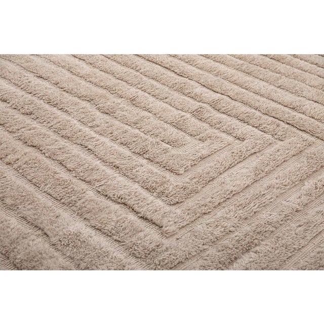 Layer upon layer of concentric lines nest inward across this light taupe rug, drawing the eye steadily toward its quiet...