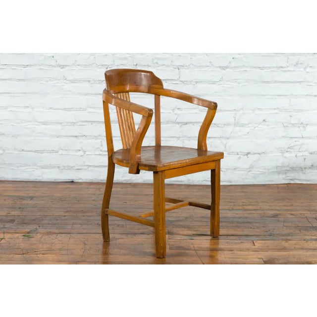A Chinese wooden horseshoe armchair from the early 20th century with open back and arms, reeded splat and H-Form cross...
