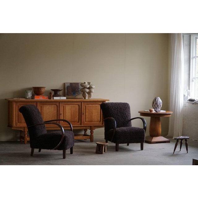 A beautiful pair of curved lounge chairs, reupholstered in shearling lambswool, designed by a Danish cabinetmaker in the...
