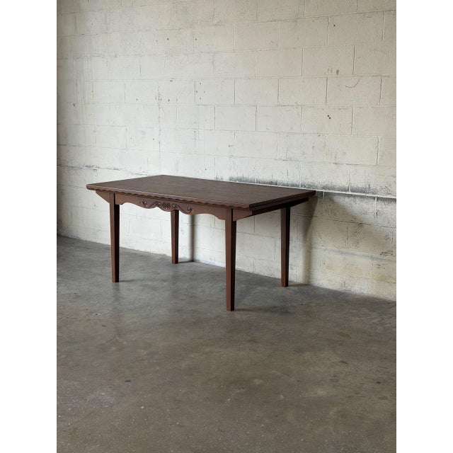 This rectangular dining table features an extendable design with two pull-out leaves. The frame is distinguished by a...