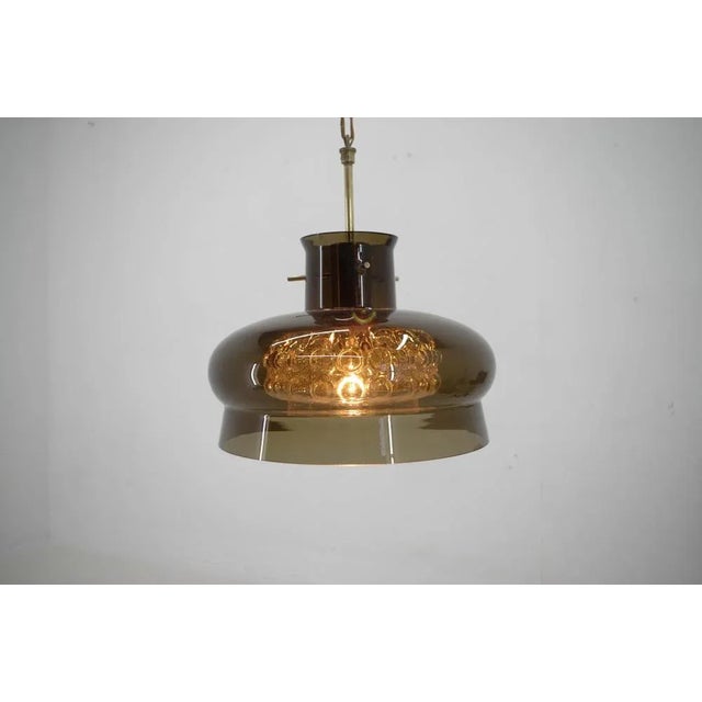 Glass pendant by carl fagerlund fro orrefors, sweden. Double glass shades on brass chain. Two dents on brown glass shade...