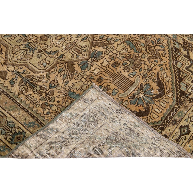 Beautiful Vintage Distressed hand-knotted wool rug with a beige field. This Persian rug has brown and turquoise accents in...