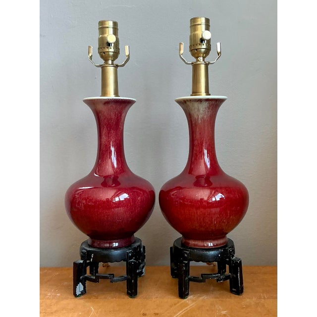 This exquisite pair of table lamps features the iconic Sang de Boeuf, or "oxblood," glaze—a classic ceramic technique...