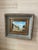 Vintage oil painting with scene of hamlet or village in pretty blues and rust color. Substantial gold decorative frame.