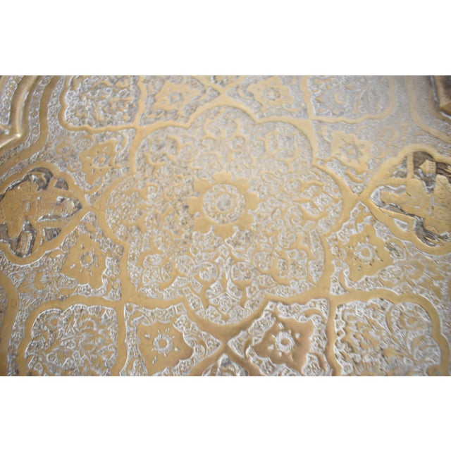 An antique, early 20th-century, Indo-Persian Mughal hammered brass round serving tray with a scalloped inset border,...