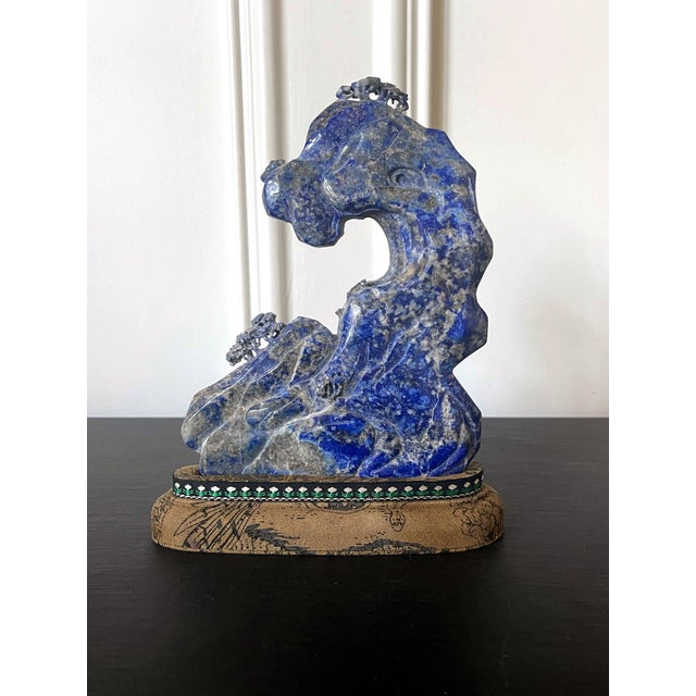 A Chinese scholar rock carved from a natural lapis stone and displayed on a brocade wrapped stand circa late 19th century...
