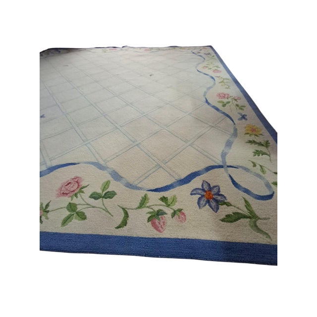 Massive George Wells hooked wool rug with blue ribbon and floral border. Rug has been professionally cleaned, but a few...