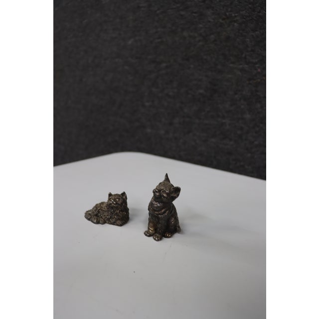 Pair of sterling silver cat figurines, each depicting a cat in a different pose. One figure features a reclining cat with...