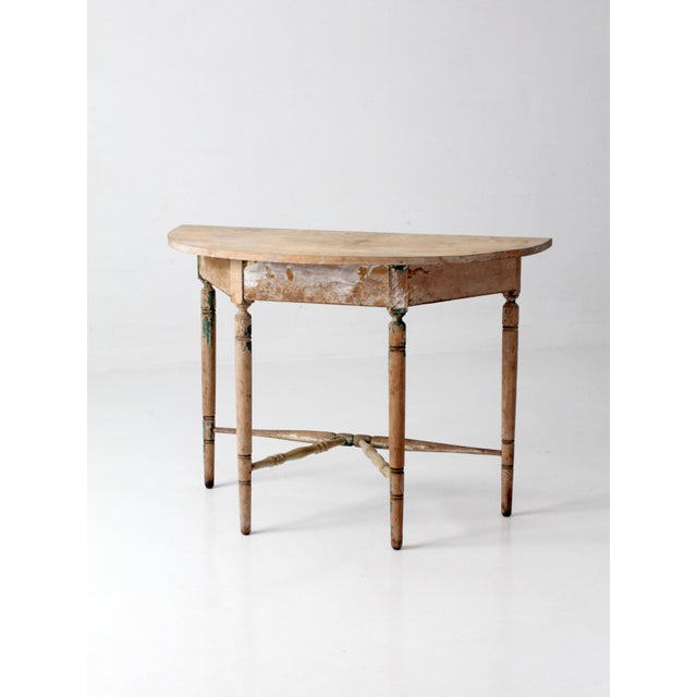 This antique 19th century demi lune table carries the worn character and understated proportions of an early American...