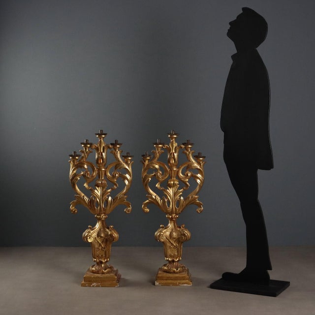 Pair of carved and gilded wooden candelabra. Five lights supported by arms decorated with scrolls, leaves, and curls,...