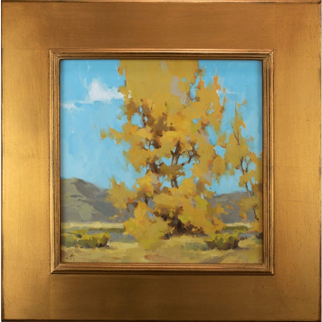 Before the Fall captures a vibrant autumn scene, showcasing a solitary tree adorned with brilliant golden leaves against a...