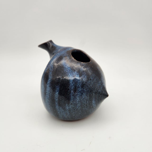 Sculptural stoneware creamer with organic bird-like form, mottled deep blue-black glaze, pinched spout, and small tail detail