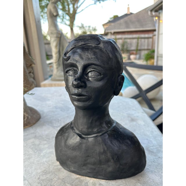 Striking vintage plaster bust depicting a young woman with softly modeled facial features and a serene expression....