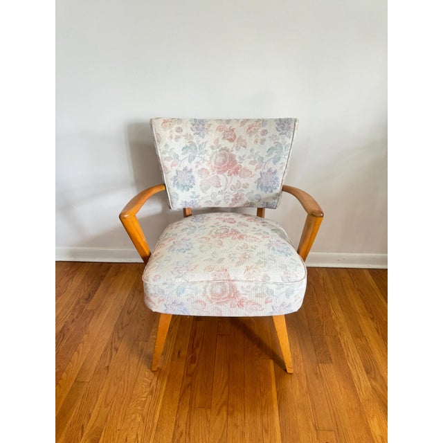 Mid-century modern armchair with a wooden frame, featuring floral upholstery.