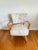Mid-century modern armchair with a wooden frame, featuring floral upholstery.