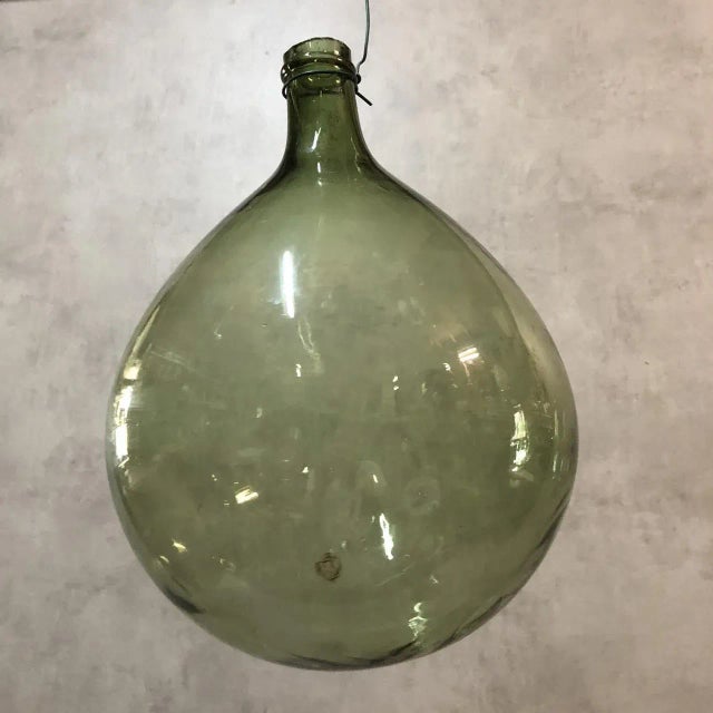 Dame-Jeanne in green blown glass. Possibility to make a hanging lamp. Will be delivered with its original basket.
