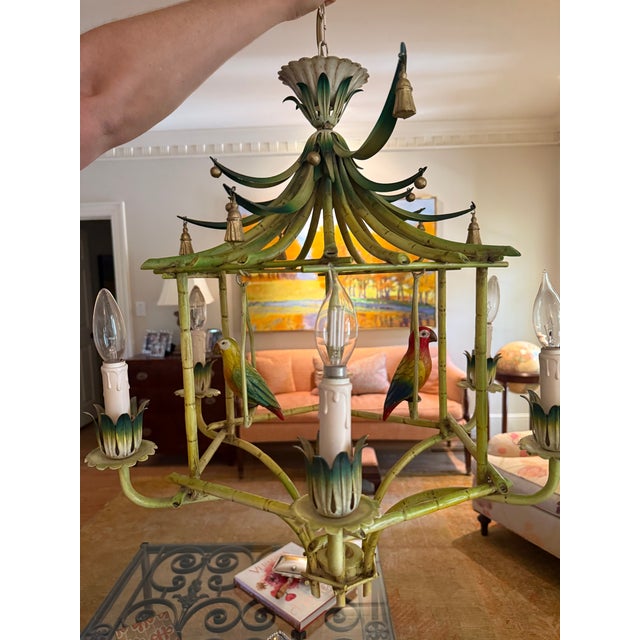 Vintage Hollywood Regency faux bamboo pagoda chandelier featuring hand-painted tropical parrot accents and whimsical...