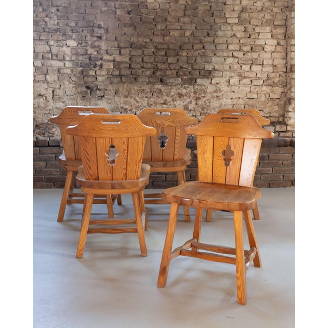Solid pine dining chairs with sculptural keyhole cut-out backrests and softly contoured top rails, likely produced in the...
