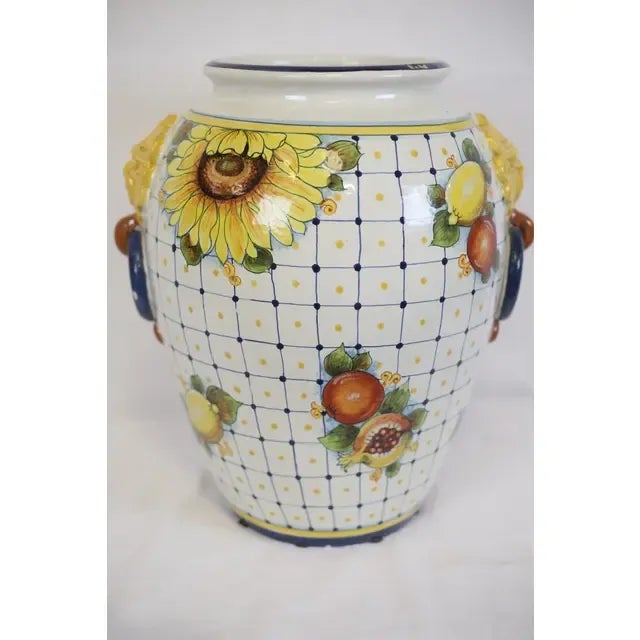 Hand-Painted ceramic vase with fruit and sunflower decoration. Accented with lion head relief handles in yellow, blue,...