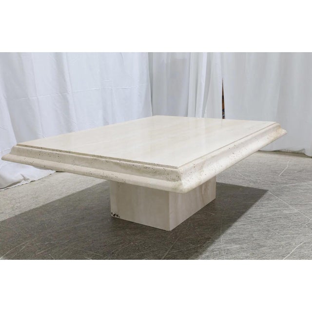Italian travertine coffee table with a two-piece construction, featuring a rectangular tabletop and a solid plinth base....