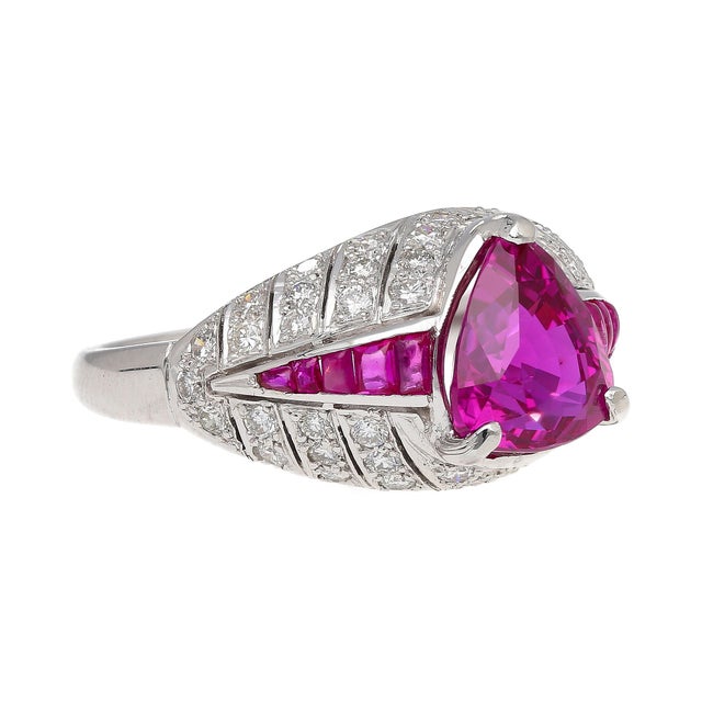 Art Deco platinum ring sets 3.04 carat trillion-cut purplish pink ruby, complemented by 10 square-cut ruby side stones and...