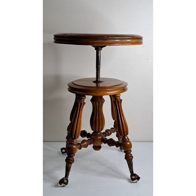 Antique H. Holtzman & Sons adjustable swivel piano stool featuring an ornate carved wood tripod base, turned and reeded...