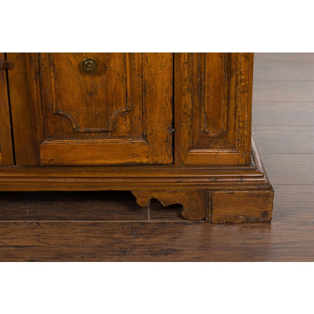 An Italian walnut credenza from the 18th century, with four drawers and two petite doors. Introducing an exquisite piece...