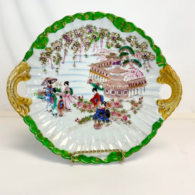 This is a pretty Mid-Century Chinoiserie Japanese Decorative Bowl. It features Geisha girls and two side handles. The rim...