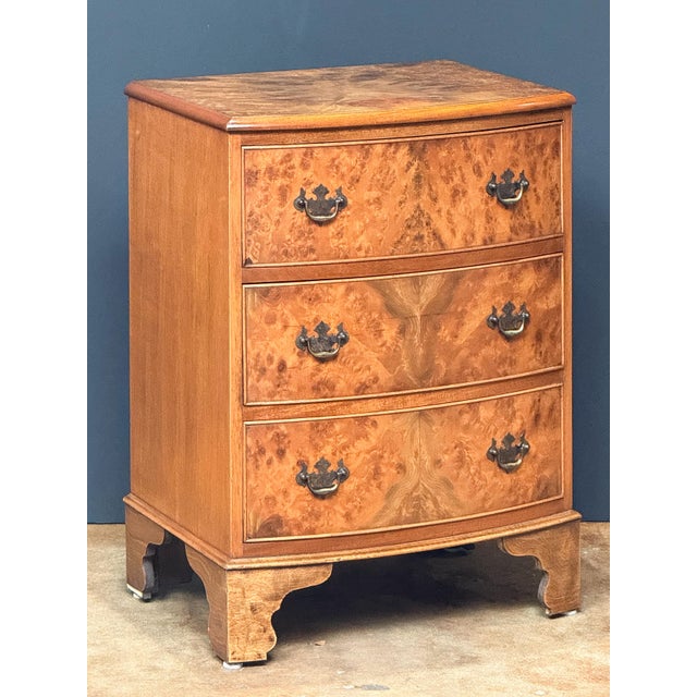 A handsome English bow-fronted small chest of burr or burled walnut from the Edwardian era, featuring a moulded top over a...