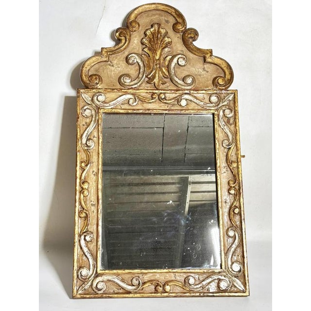 A 20th-century French mirror, crafted from carved and patinated wood, richly adorned with scrolls and foliate motifs...