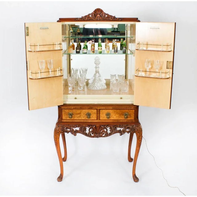 This is a fantastic vintage Queen Anne Revival burr walnut cocktail cabinet with wonderful hand carved decoration,...