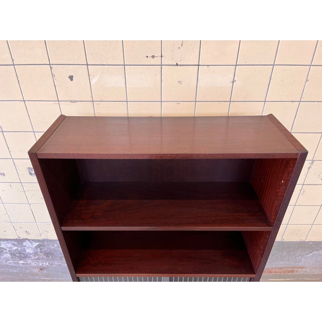 This vintage Danish bookcase features a refined design with an integrated glass display section, offering both storage and...