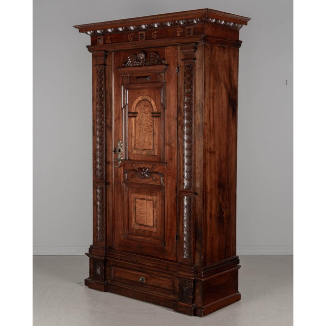 Made of solid walnut and veneers of walnut with pine as a secondary wood. The door has marquetry inlaid architectural...