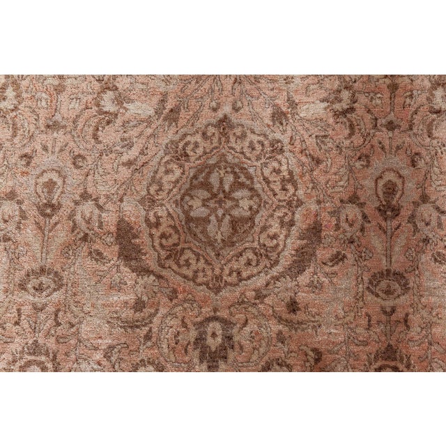 An early 20th century Persian Tabriz rug, the abrashed pale rust field with an allover trellis design of medallions, leafy...