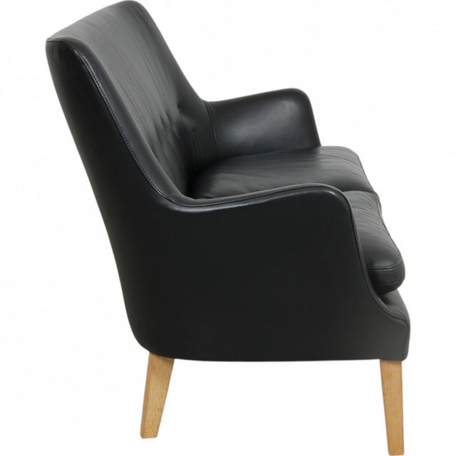 Arne Vodder 2.seater AV5 sofa upholstered in black leather and with legs of oak. The sofa is from around 2017 and appears...