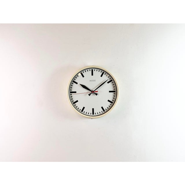 Wall clock produced by Van Doorn in Netherlands during the 1960s. It features a beige iron frame, an iron dial, an...
