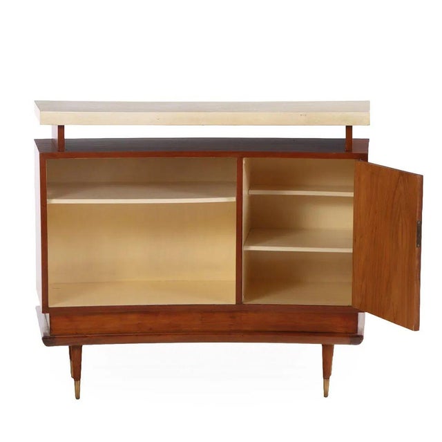 A mid-century modern bar ensemble featuring a mahogany bar and pair of counter stools. The bar showcases an elegant curved...