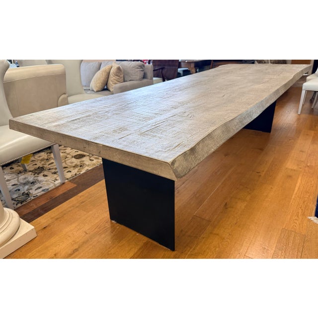 A striking Restoration Hardware dining table that pairs an expansive, character-rich wood top with sculptural black metal...