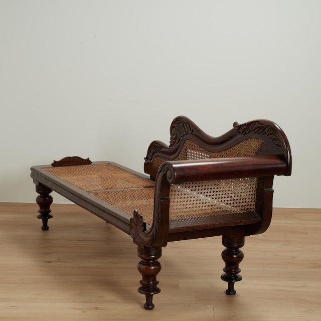 Dashing 19th century West Indies chaise lounge handcrafted in mahogany in elegant form with carved acanthus leaves, caned...