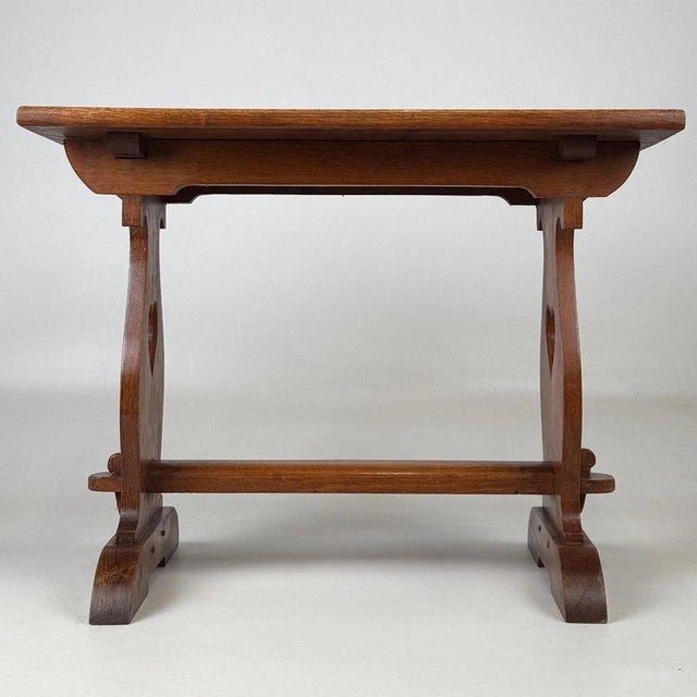 A charming early 20th-century English coffee table in the Arts and Crafts tradition, finely crafted from golden oak and...